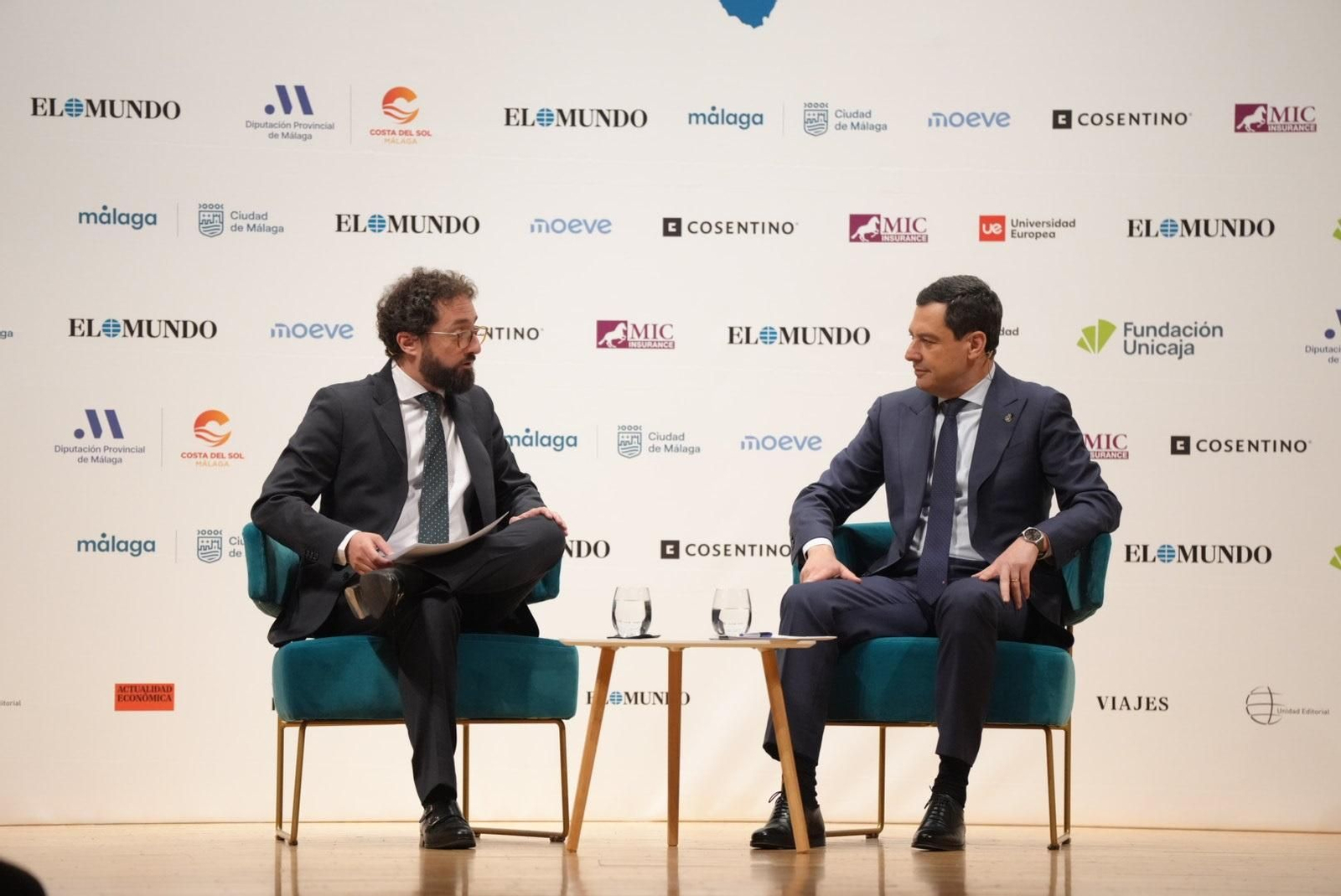 El presidente de la Junta de Andalucía, Juanma Moreno, conversa con el director de El Mundo, Joaquín Manso, en un foro informativo en Málaga.